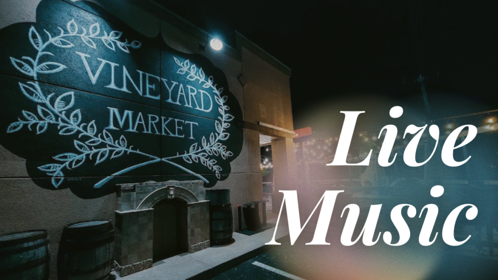 Vineyard Market wreath logo glowing at night with the lit patio in the background, creating a warm and inviting fall atmosphere.