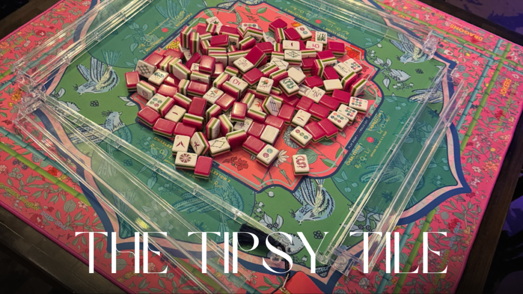 Red, white, and green American Mahjong set arranged on a wooden dining table, ready for open play in a cozy indoor setting.